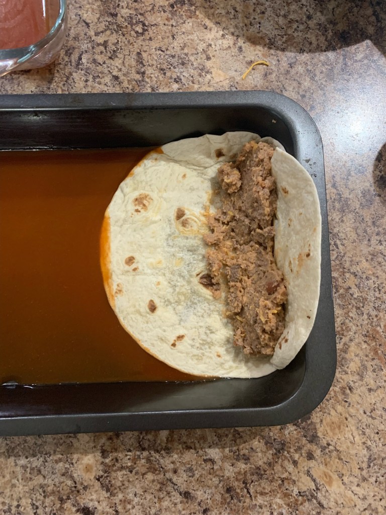 Place fried tortilla at end of pan, add filling. Fold over to cover beans, then roll.
