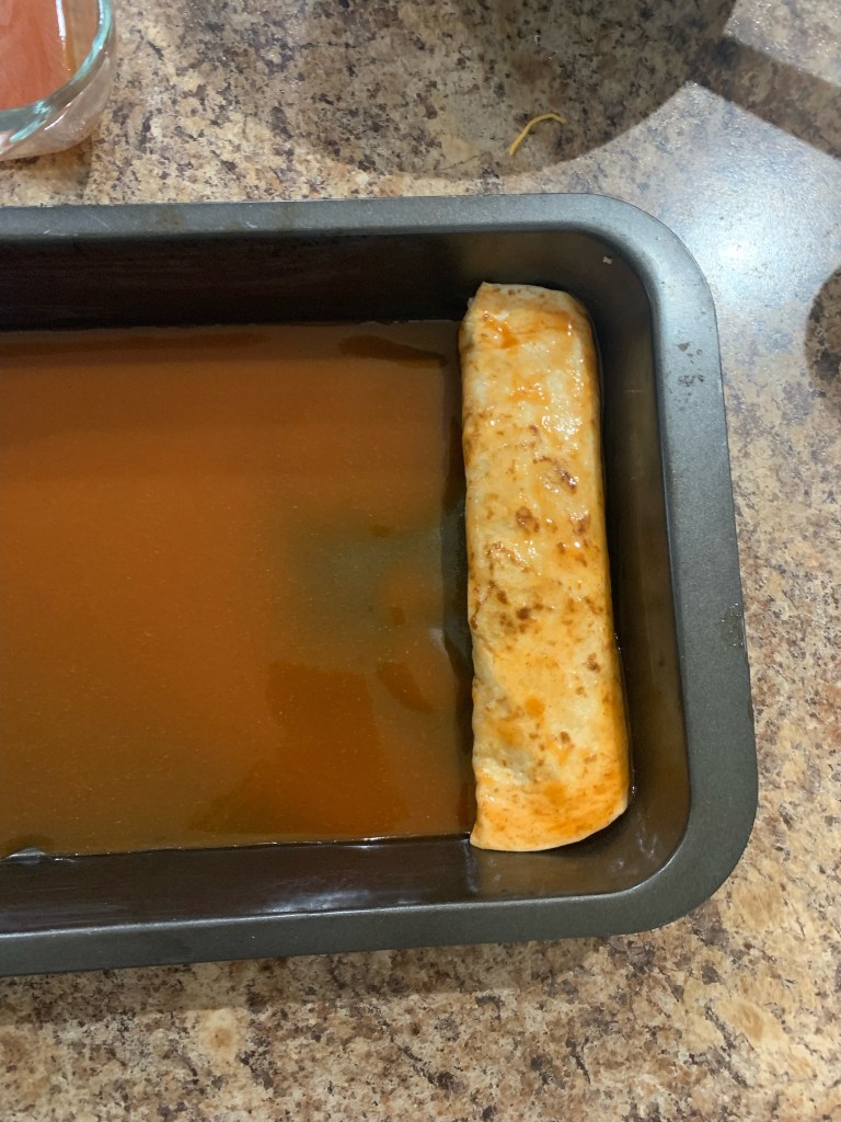 A rolled up enchilada, ready to be covered in sauce.
